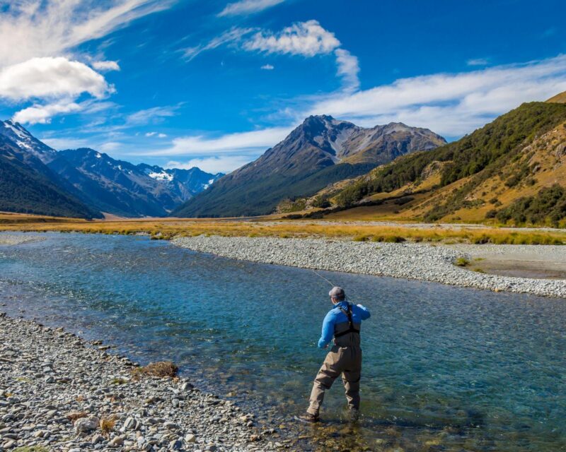 A fly fisherman casting on a mountain stream in New Zealand