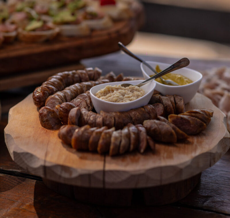 Kranjska klobasa or sausage is being served at an event, chopped sausage with mustard and other condiments. Typical slovenian food served in the mountains.