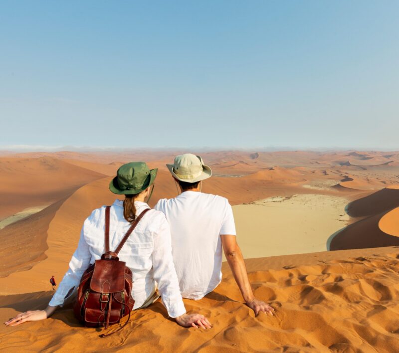 Travellers in Africa, couple on romantic vacation in Namibia, looking at beautiful Namib desert landscape
