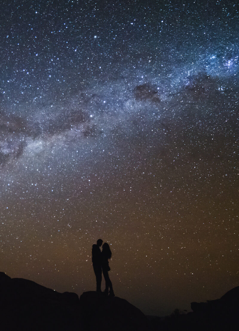 Landscape with Milky Way. Night sky with stars and silhouette of a couple kissing on the mountain.
