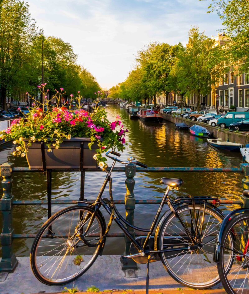 Bike parked at a bridge over a canal decorated with flowers in Amsterdam