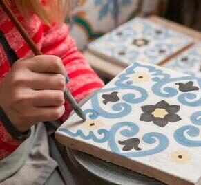 A pottery decorator painting a ceramic tile with floral motifs in his work table in Caltagirone, Sicily is one of our best places to visit in 2026