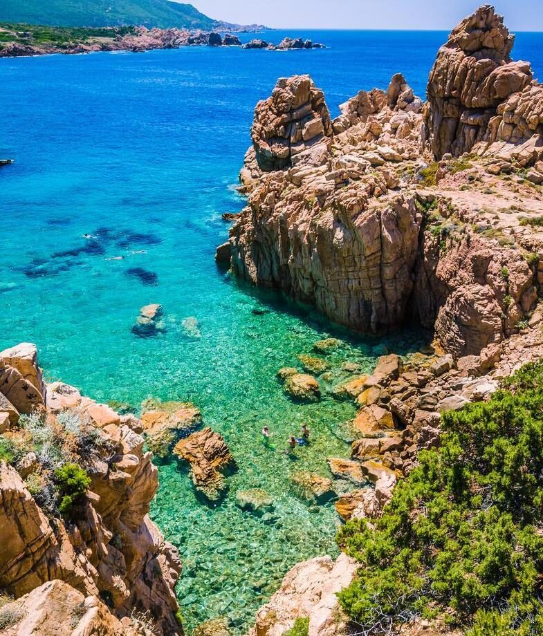 Ancient ruins overlooking Mount Etna in Sicily and turquoise waters framed by rugged cliffs along Sardinia’s coast.