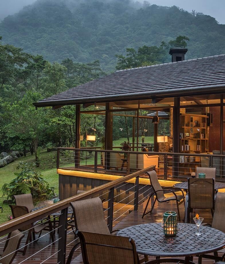 The glass-fronted terrace of El Silencio Lodge & Spa surrounded by the characteristic misty cloud forest of Costa Rica, and the swimming pool of Chablé Resort in Mexico on a sunny day.