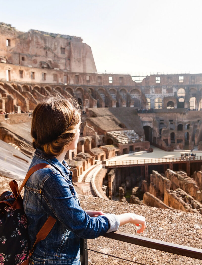 A young woman with a backpack exploring inside the Colosseum.