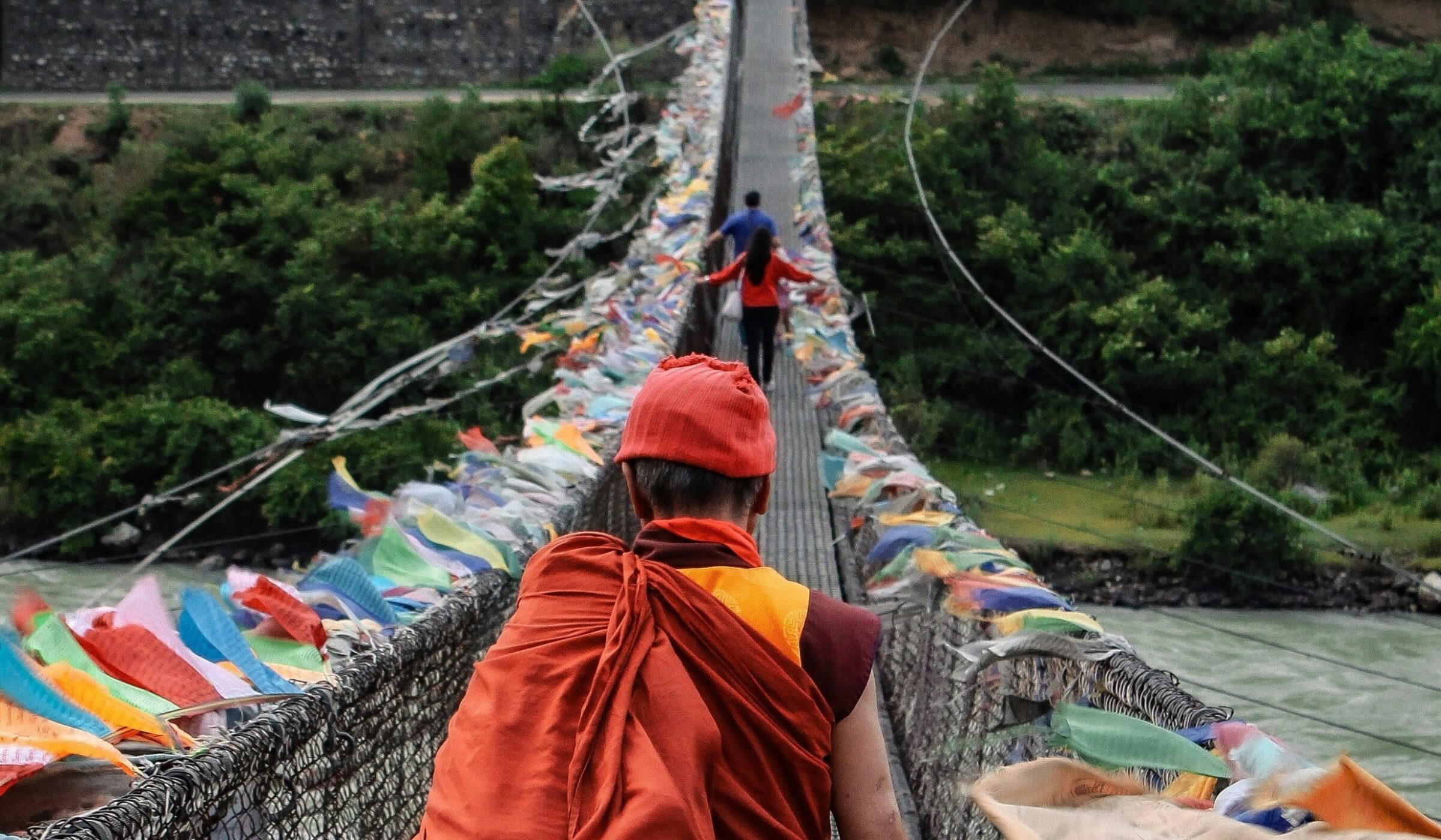A family in Bhutan crossing the bridge with traditional flags