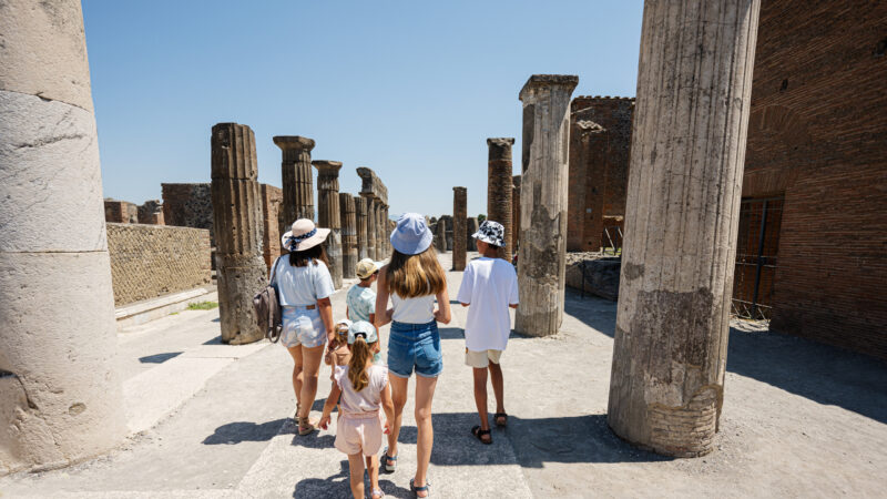 Back of family tourist walking at Pompeii ancient city Italy