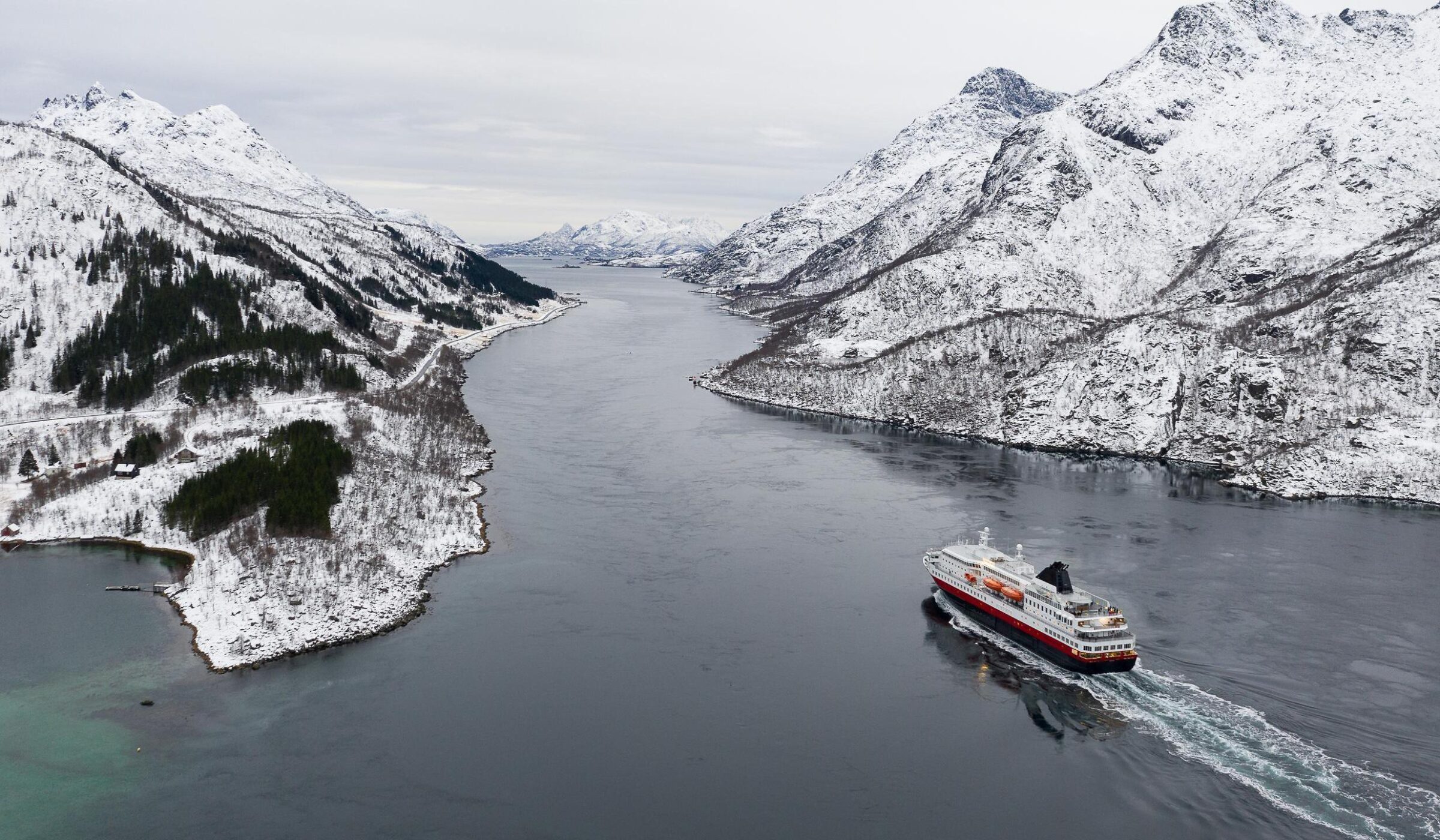 Aerial view of fjord in cold winter weather with Hurtigruten ferry turist boat on the sea.