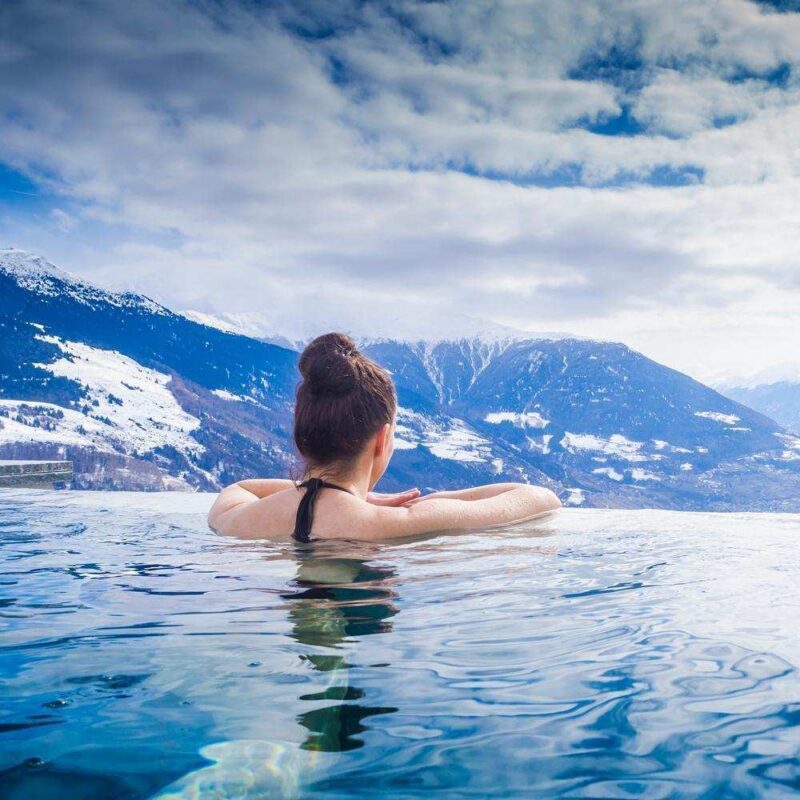 Frau geniesst Bergpanorama im Winter vom Pool aus