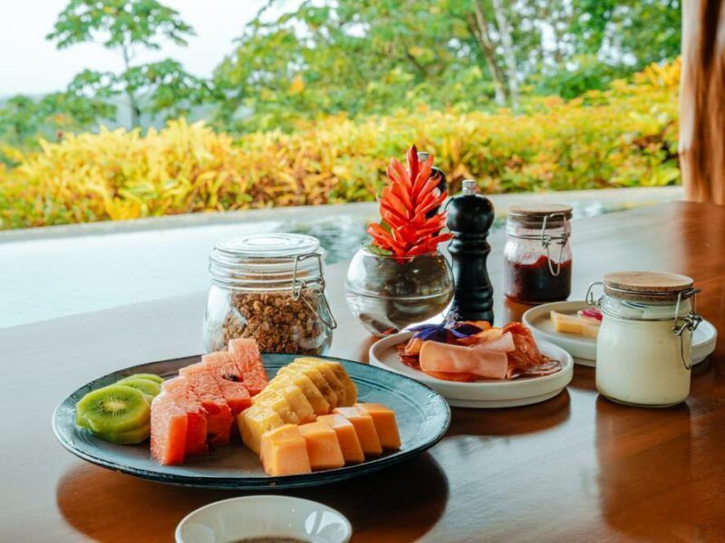 A fresh breakfast spread of tropical fruits and granola jars on a wooden table during luxury Family trips.