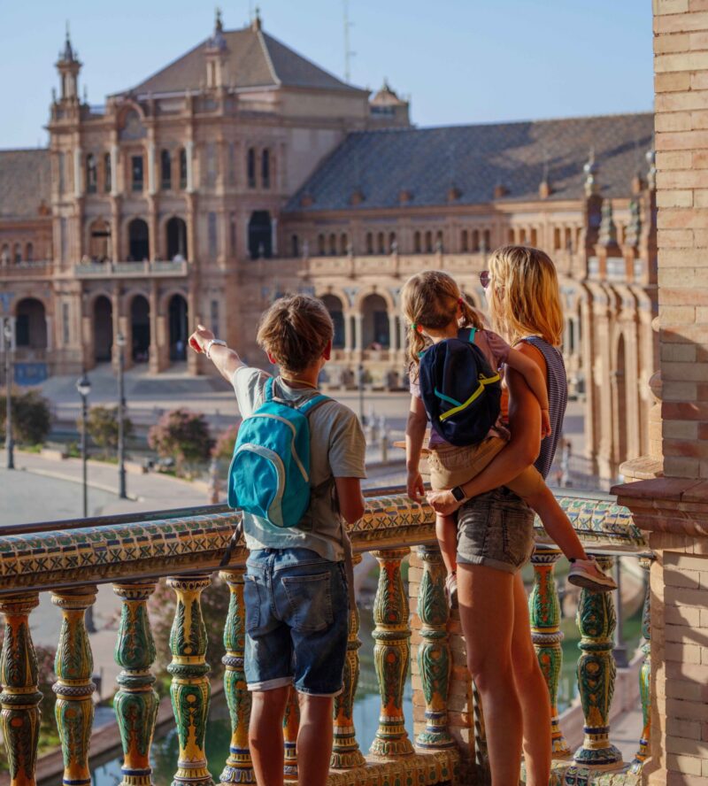 Family with kids in Sevilla overlook magnificent plaza de Espana in sunset light during their summer vacations in Spain