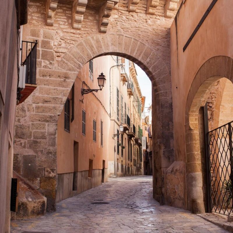 Old street of Palma de Mallorca with stone archways overhead
