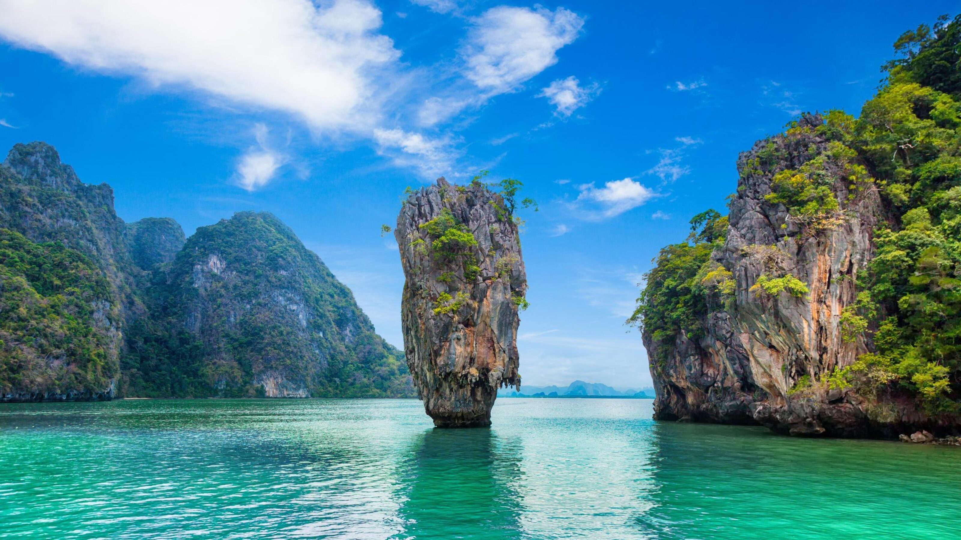 Famous limestone rock formation in clear turquoise water under a blue sky in Phuket, Thailand.