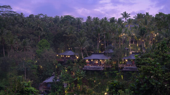 Luxury tented villas with glowing lights nestled in a lush, dense tropical jungle under a purple twilight sky.