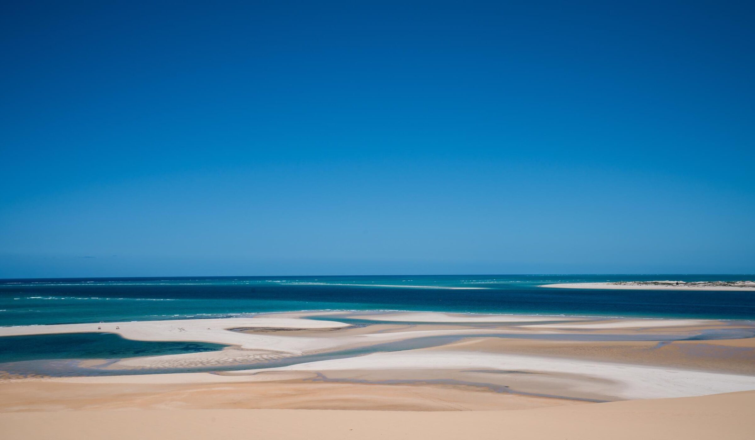 Wide view of sandbars and turquoise ocean water under a clear blue sky in the Bazaruto Archipelago, Mozambique.
