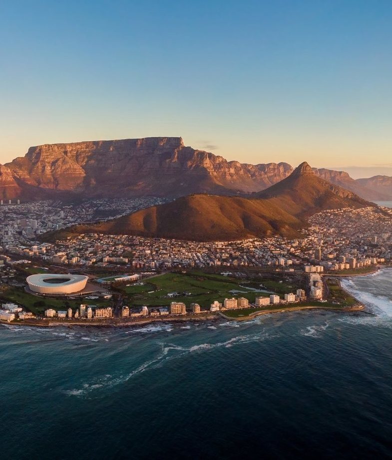 A young wildebeest calf nursing from its mother in Serengeti and an expansive aerial view of Cape Town featuring Table Mountain, Lionx27;s Head and the coastal city stadaium.