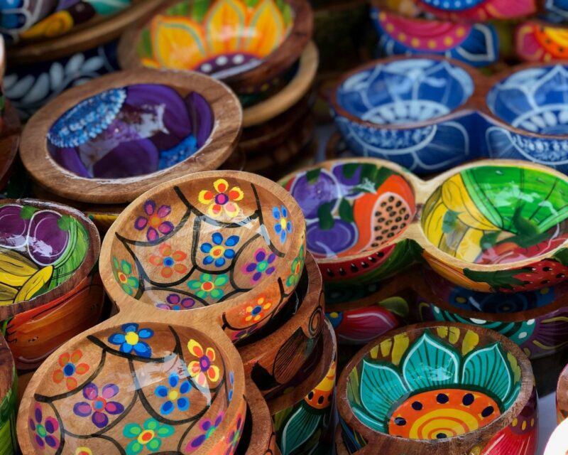 Colorful hand-painted wooden bowls with floral patterns at a market in Mexico.