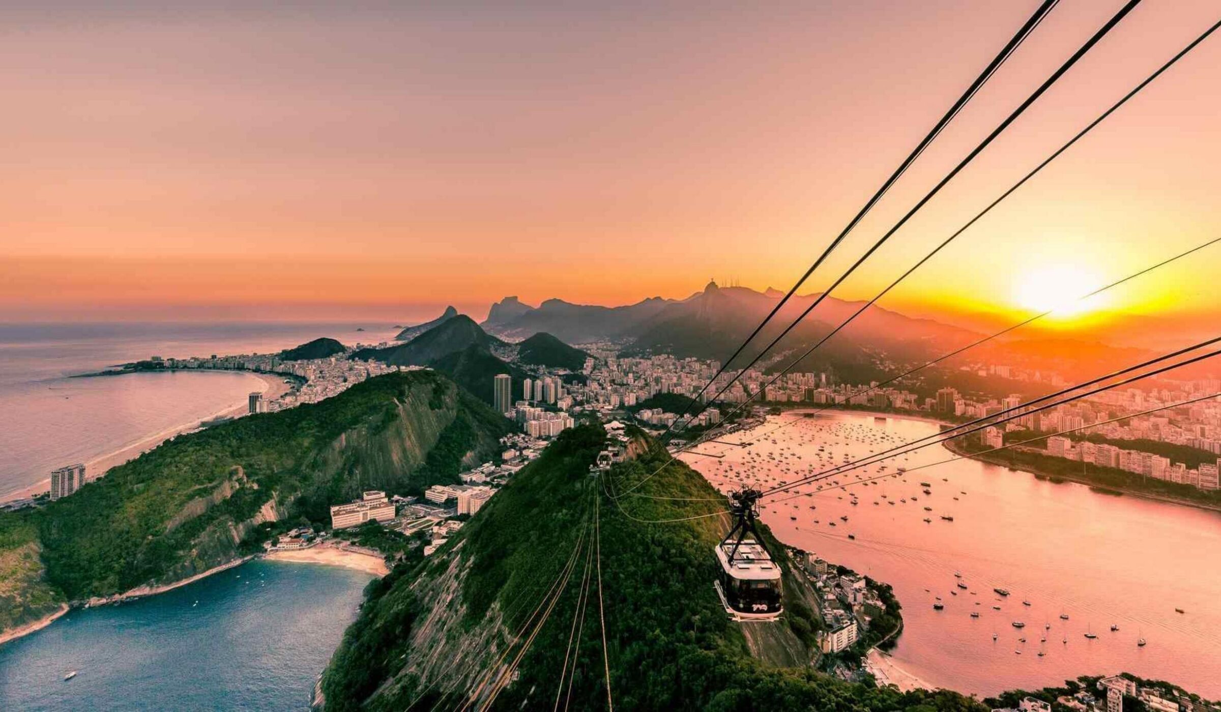 Panoramic sunset view of Sugarloaf Mountain and the city lights of Rio de Janeiro, Brazil.