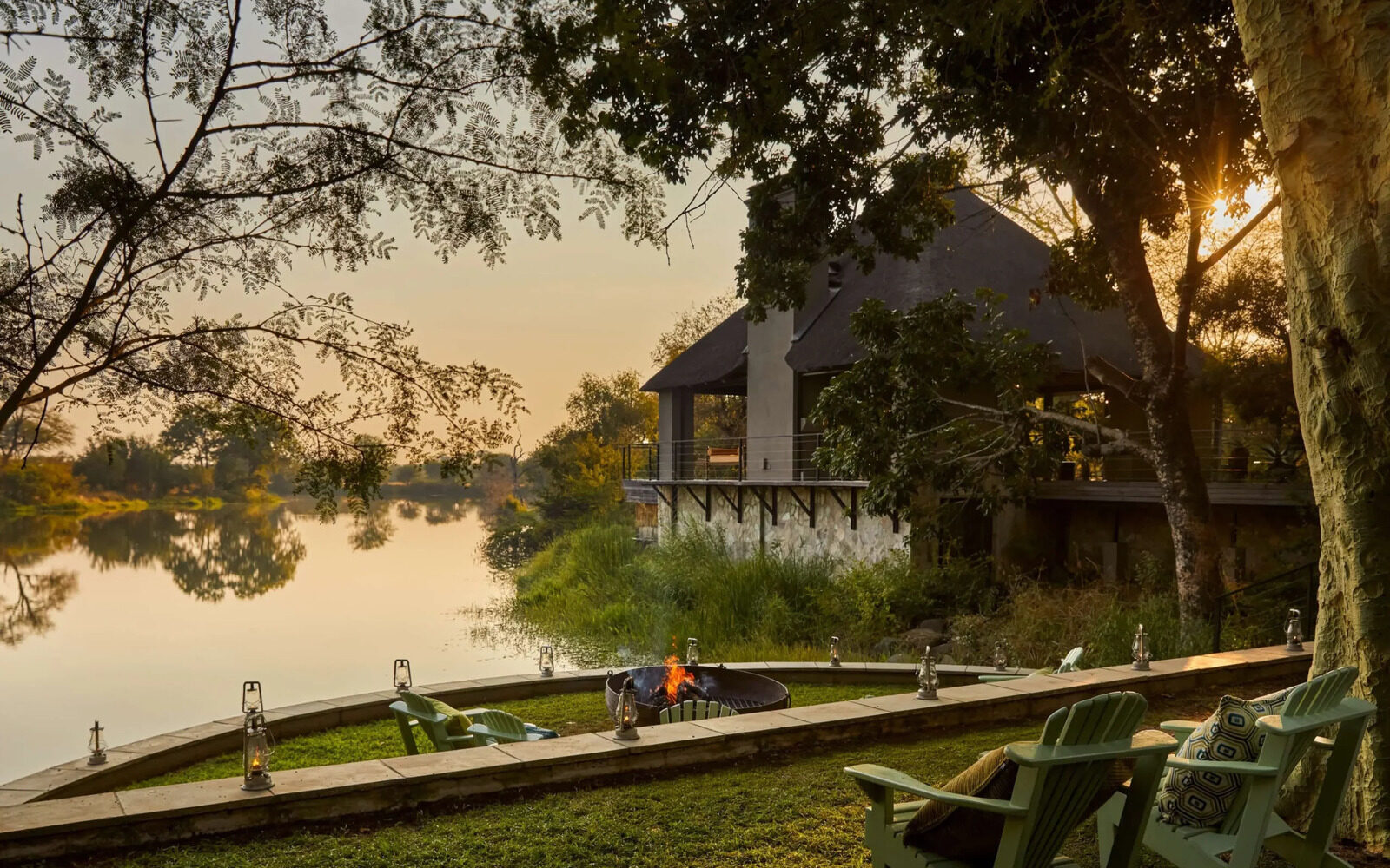The riverside firepit and garden at Royal Malewane Waterside House in the soft light of sunset.