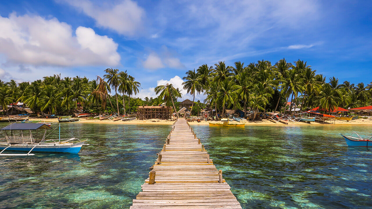 The wooden Cloud 9 surfing boardwalk extends over the shallow coastal waters of Siargao Island in the Philippines.