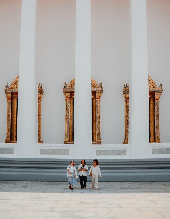 A guide walks with two guests on a Bangkok temple tour.