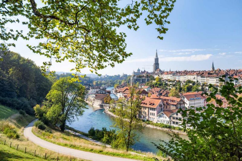 Skyline view of Bern Old Town with historic buildings, a winding river, and church spires under a clear blue sky.
