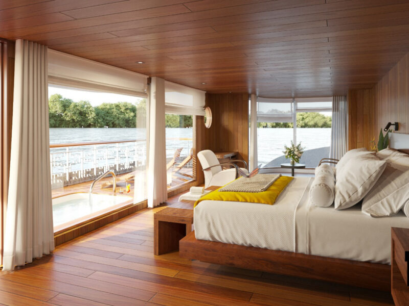 A luxury cabin on a latin america expedition cruise features a bed, large windows, and a private deck with a small pool.