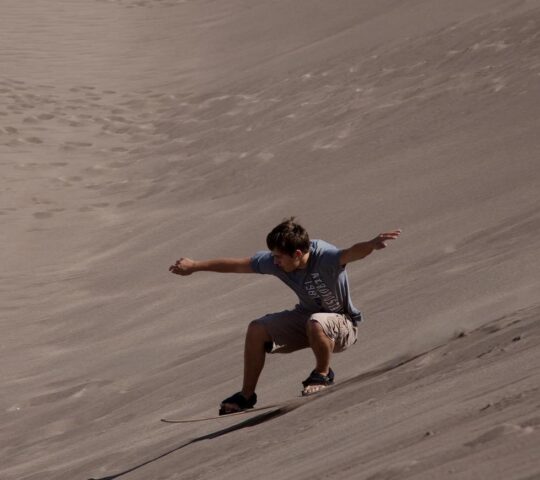 Zoom down towering dunes on a sandboard