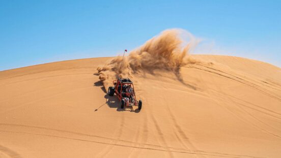 A dune buggy riding down a sand dune in the Sahara desert