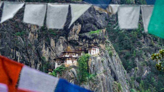 Paro Taktsang, Tigerx27;s Nest Monastery, perched on a rocky cliffside framed by prayer flags in Bhutan.